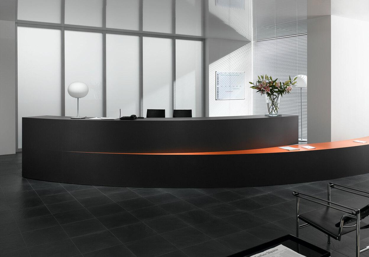 Hotelrezeption mit schwarz lackierter Empfangstheke und orangenem Kontrast