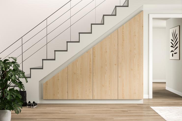 Ein großer, an die Treppe angepasster Schrank nach Maß mit heller Holzoptik verleiht dem Eingangsbereich ein organisches und funktionales Design.